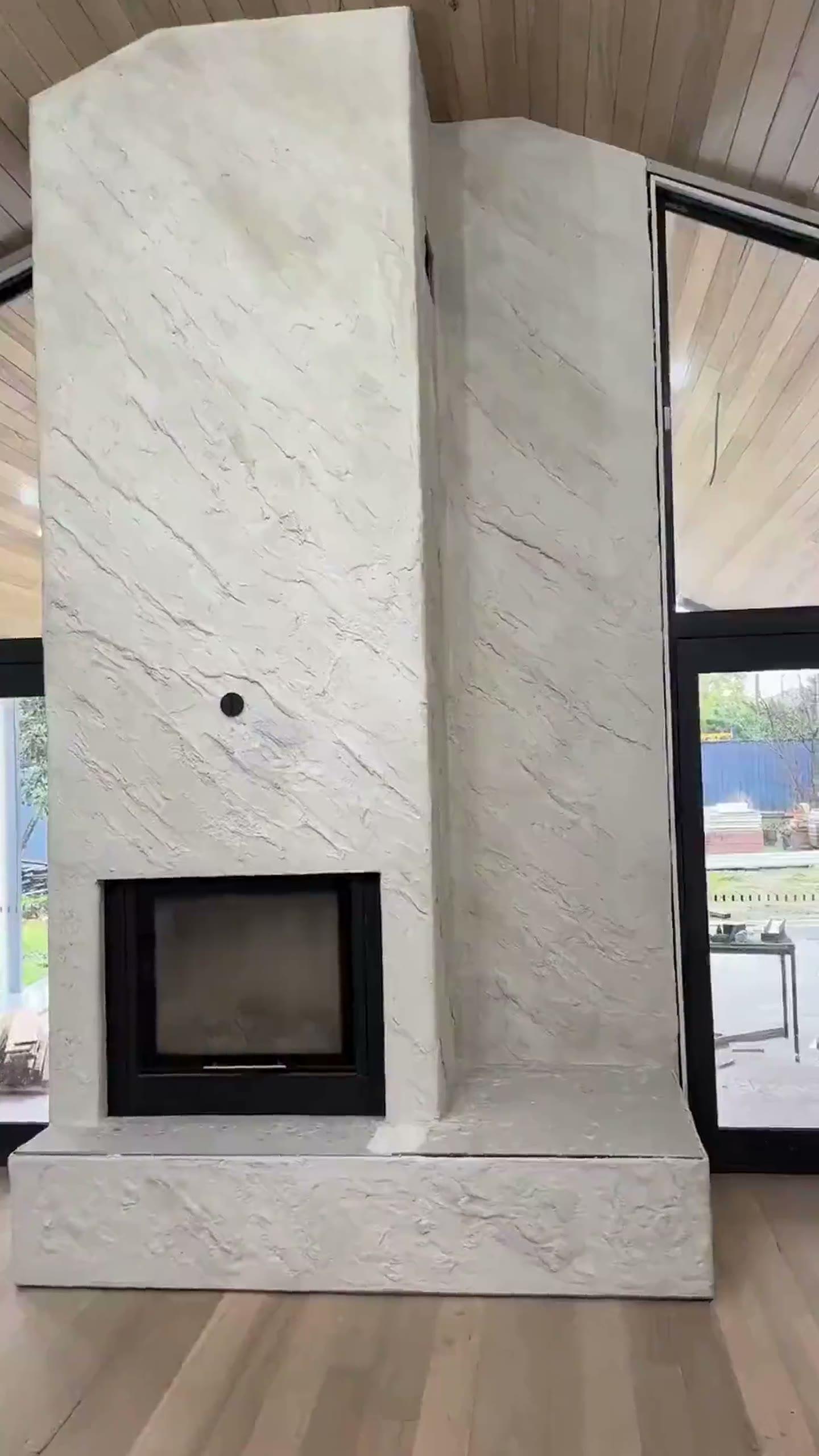 Heavily textured matte lime plaster fireplace — chimney breast, firebox surround and hearth finished in warm bone, with a smoother banded return